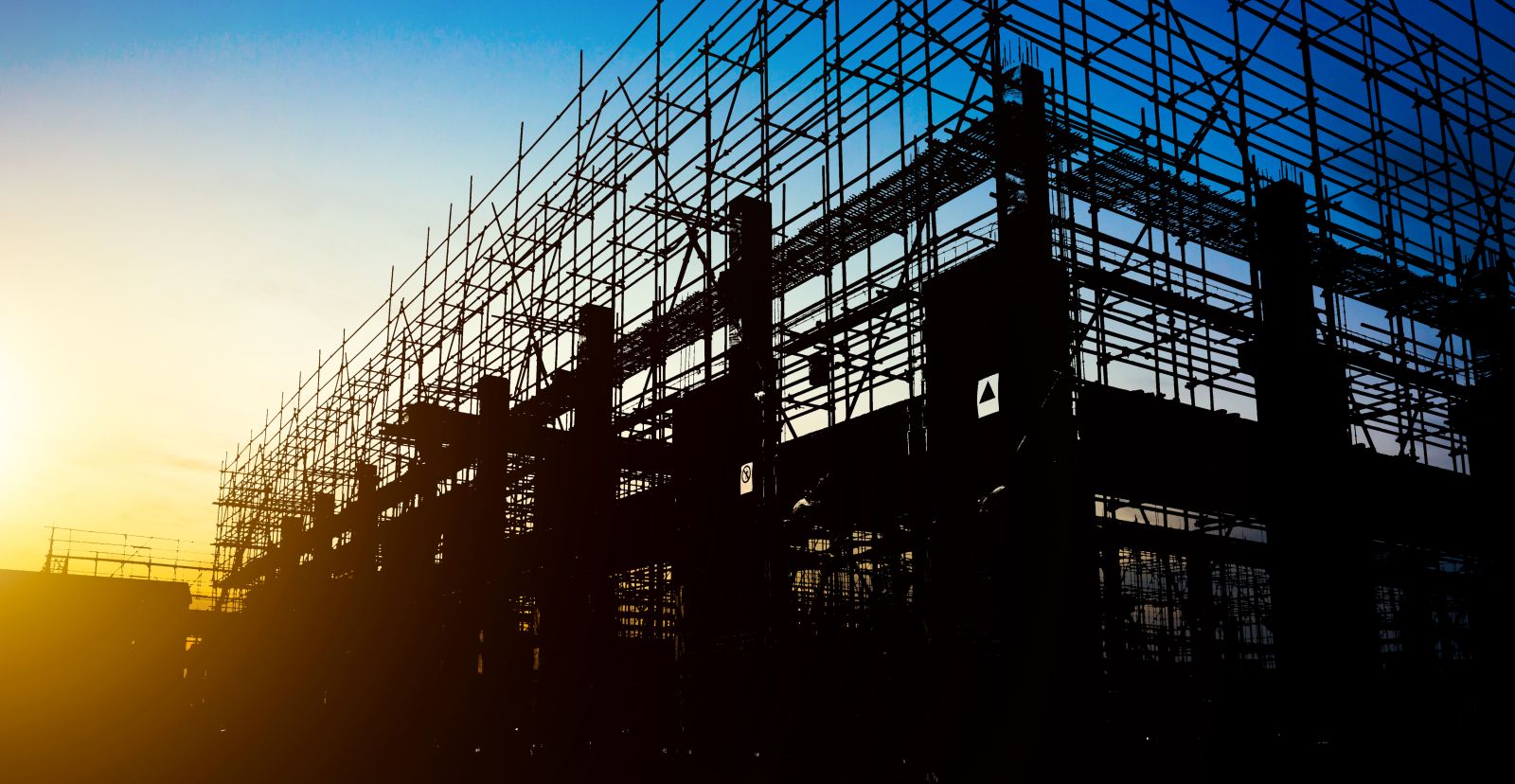 Steel scaffolding of a building under construction against a sunset sky
